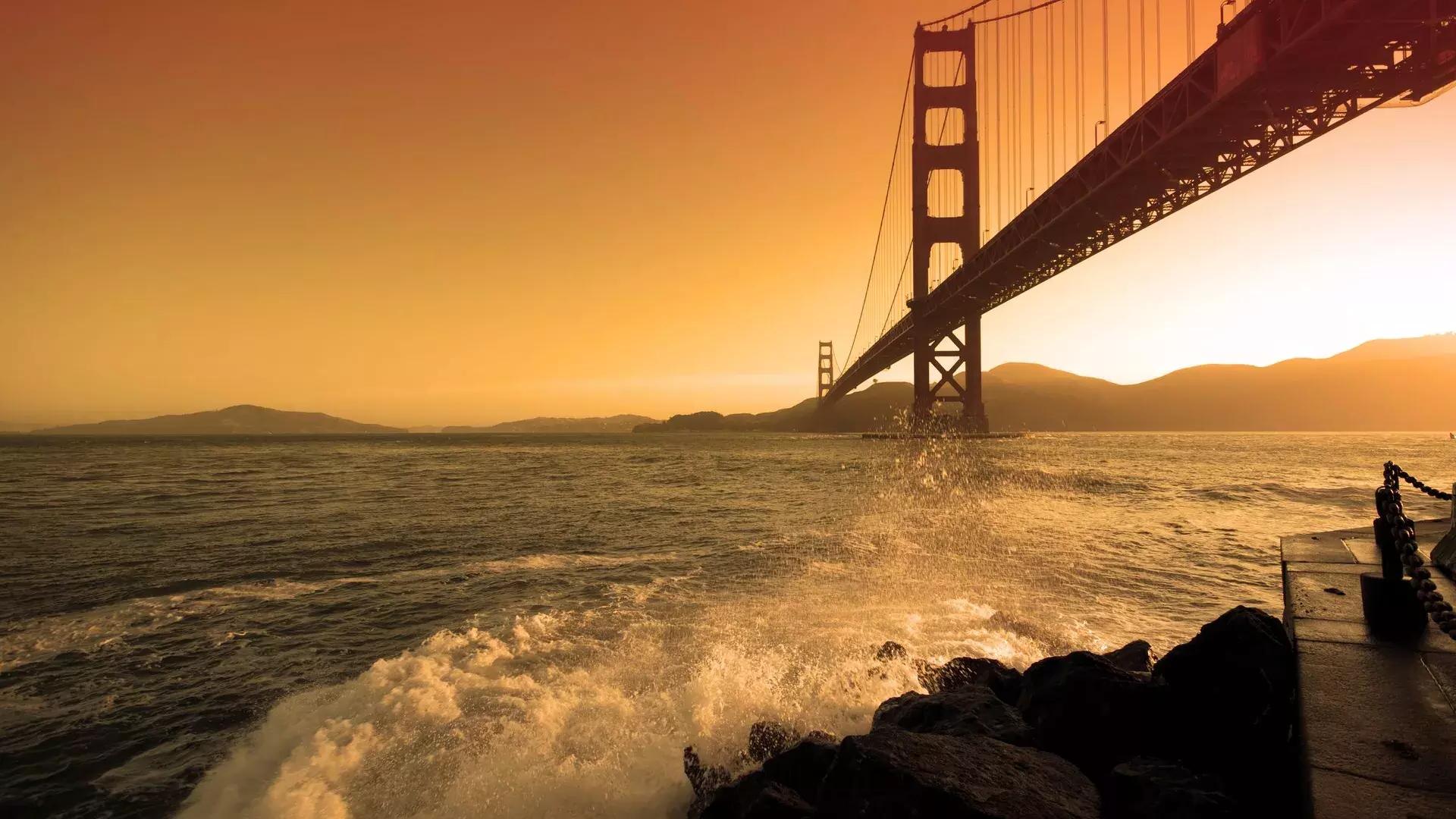 Bei Sonnenuntergang krachen Wellen in der Nähe von Fort Point unter der Golden Gate Bridge.