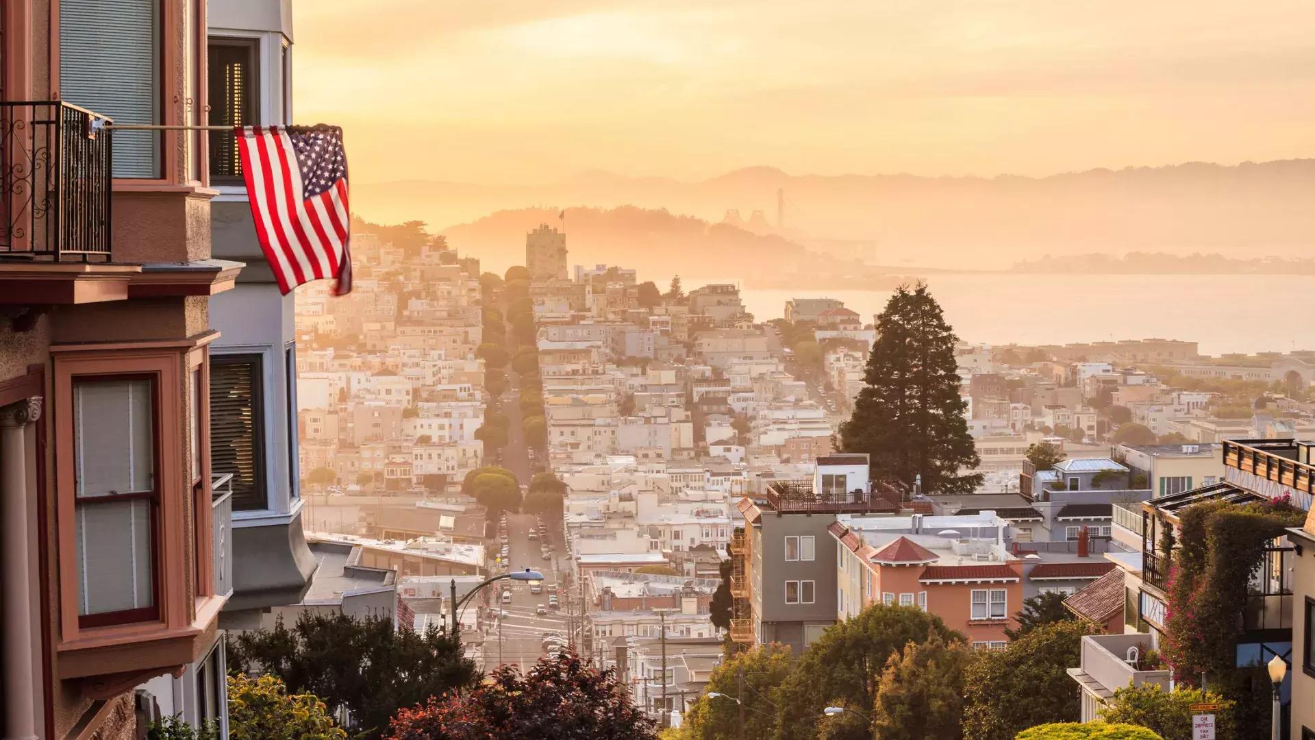 Ein Blick auf San Francisco von der Spitze eines Hügels, mit einer wehenden amerikanischen Flagge im Vordergrund.